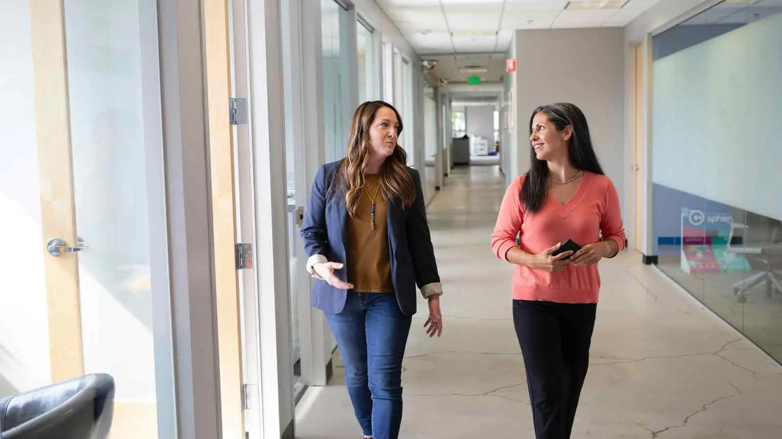 Colleagues discussing an online encumbrance certificate request in an office corridor