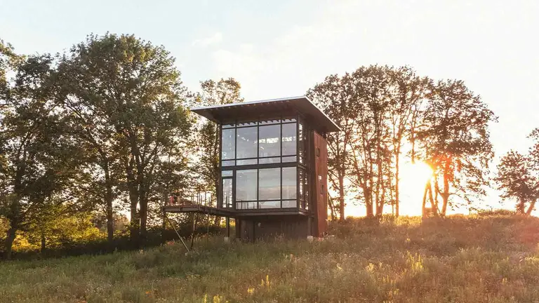 Glass cabin at sunset in a meadow, the kind of property a title search protects